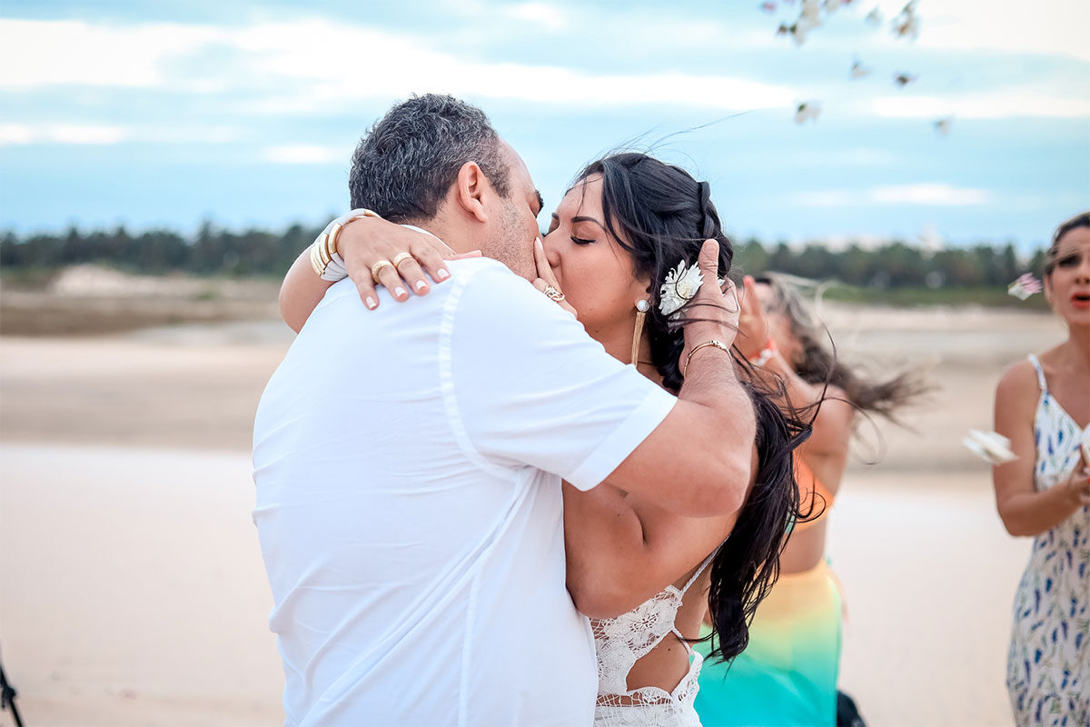 Casal de noivos se beijando na praia