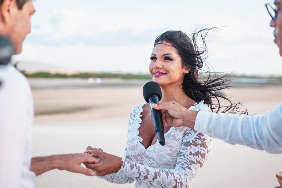 Noiva e noivo trocando alianças em cerimônia de casamento na praia