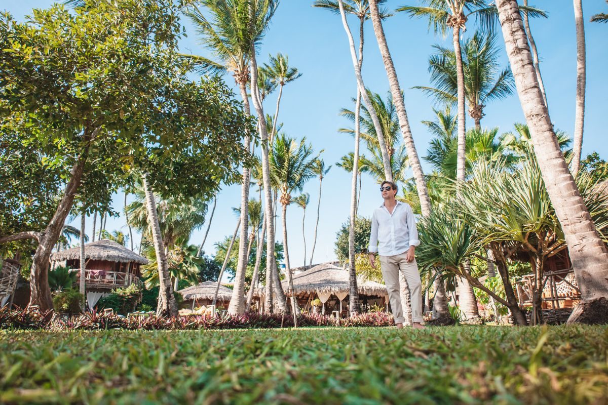 Noivo em pé, em jardim verdejante, cheio de coqueiros em Jericoacoara